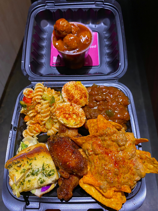 baby shower plate with pasta salad, deviled eggs, baked beans, turkey and cheese sliders, chicken wings, and rotel dip, and meatballs